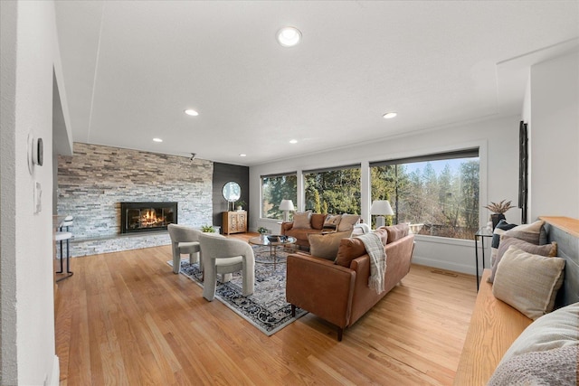 living area with baseboards, light wood finished floors, a fireplace, and recessed lighting