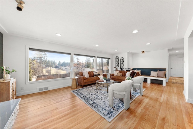 living area featuring visible vents, baseboards, light wood-style flooring, a textured ceiling, and recessed lighting