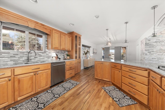 kitchen with decorative light fixtures, light wood finished floors, decorative backsplash, a sink, and dishwasher