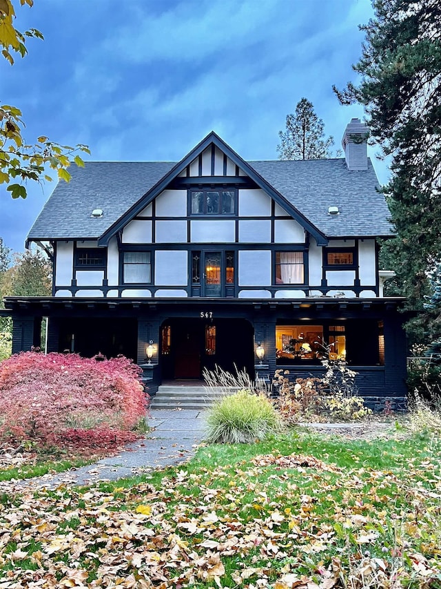 back of house with a shingled roof and a chimney