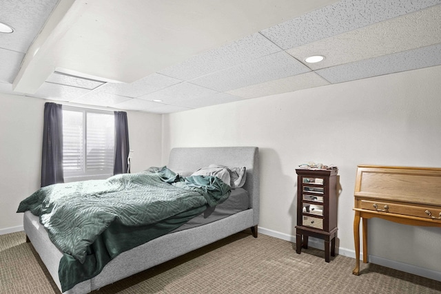 bedroom with baseboards, a drop ceiling, and light colored carpet