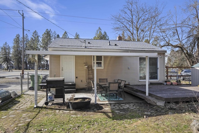 back of property with a chimney, a wooden deck, and fence
