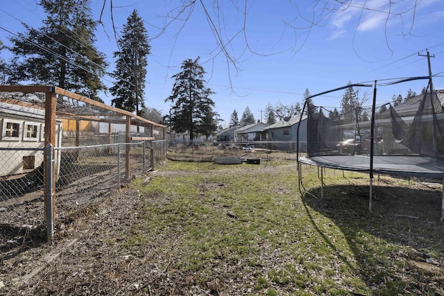 view of yard featuring a fenced backyard, a trampoline, and a residential view