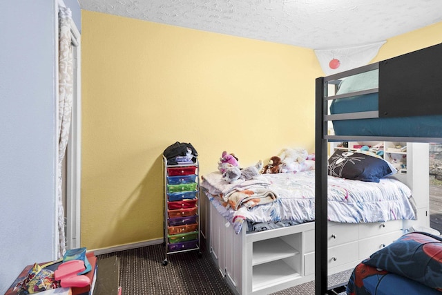 bedroom with baseboards, a textured ceiling, and carpet