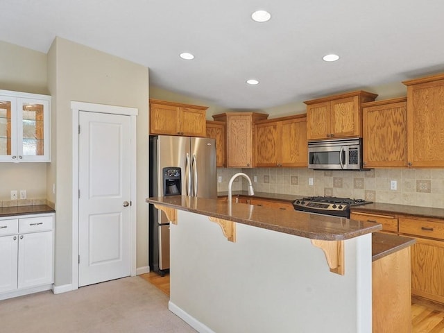 kitchen with appliances with stainless steel finishes, a sink, a breakfast bar area, and tasteful backsplash