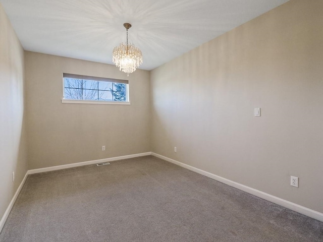 empty room featuring a notable chandelier, carpet floors, visible vents, and baseboards