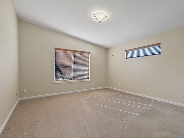 carpeted empty room featuring baseboards