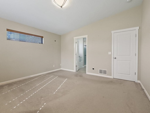 carpeted empty room featuring vaulted ceiling, visible vents, and baseboards