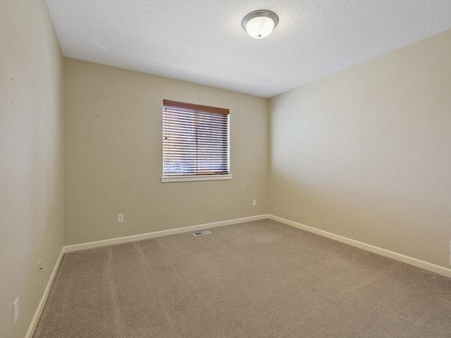 carpeted spare room with visible vents and baseboards