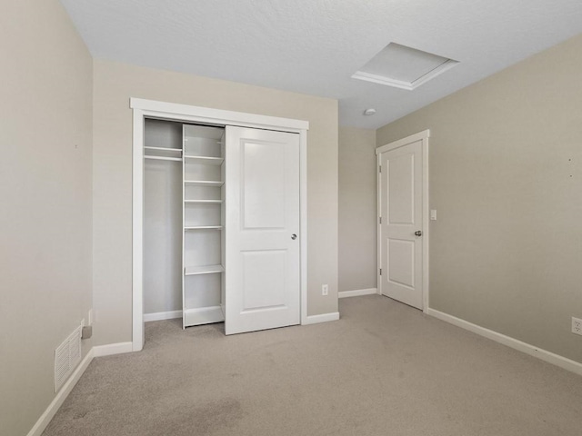 unfurnished bedroom featuring visible vents, a closet, attic access, and baseboards