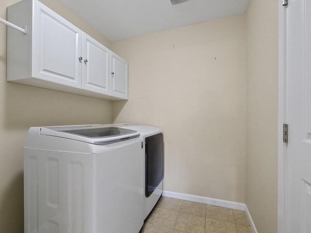 laundry area with light tile patterned floors, washing machine and dryer, cabinet space, and baseboards