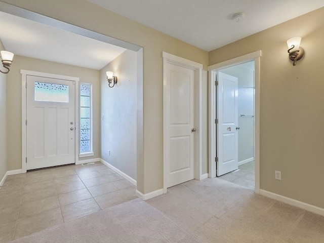 entryway with light carpet, baseboards, and light tile patterned flooring