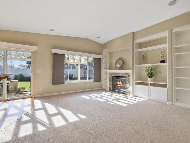 unfurnished living room with a healthy amount of sunlight, built in features, and a stone fireplace