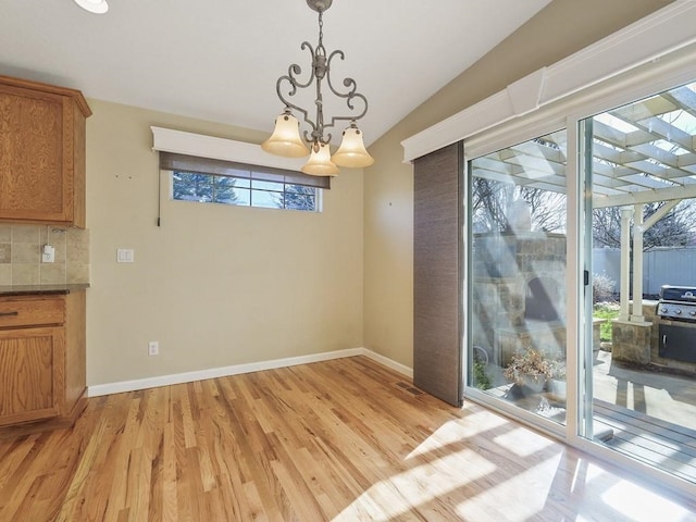 unfurnished dining area featuring baseboards, a notable chandelier, visible vents, and light wood finished floors