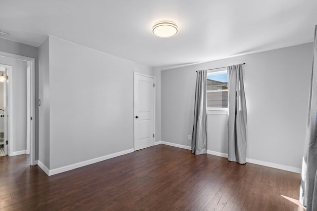 spare room featuring baseboards and wood finished floors