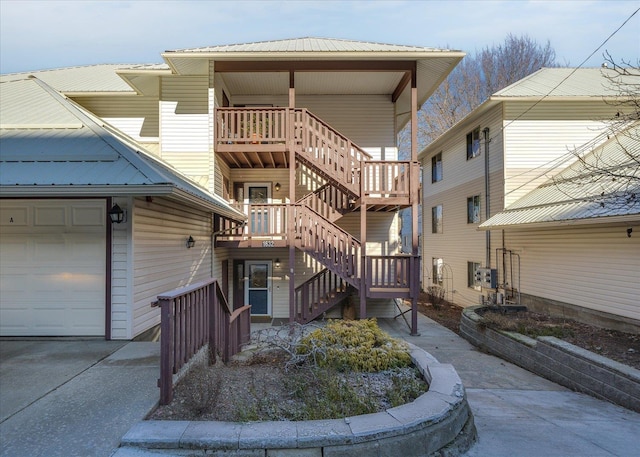 back of house featuring a garage, stairway, and metal roof