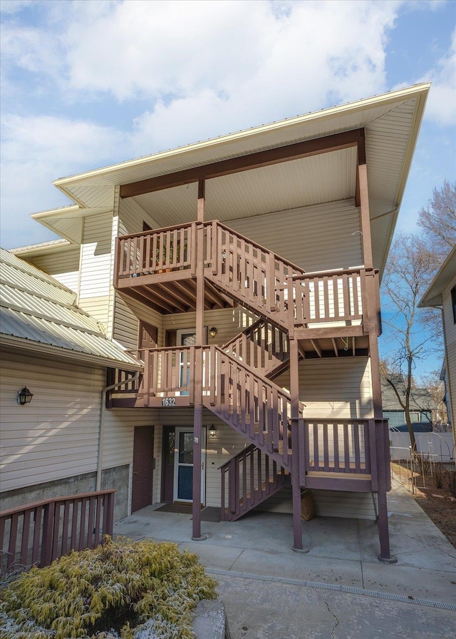 rear view of property featuring stairs and metal roof