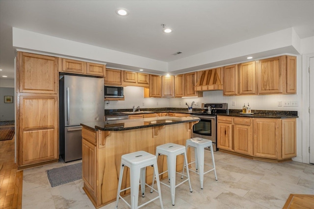 kitchen with premium range hood, a sink, a kitchen breakfast bar, appliances with stainless steel finishes, and a center island