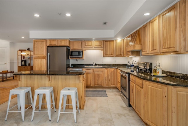 kitchen with custom range hood, appliances with stainless steel finishes, a sink, a kitchen island, and a kitchen bar