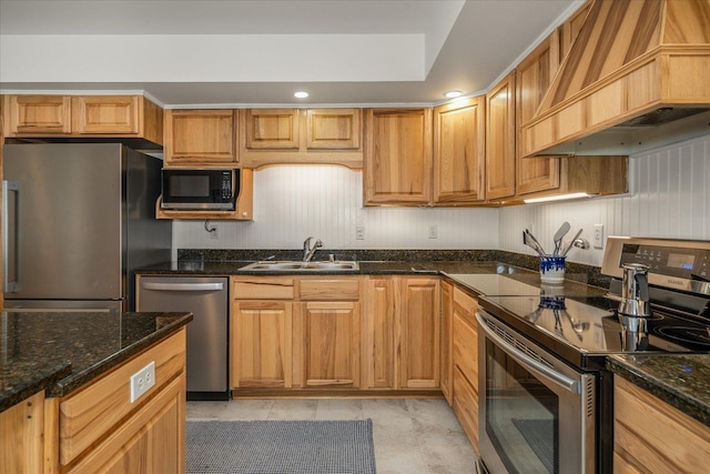 kitchen with recessed lighting, stainless steel appliances, premium range hood, a sink, and dark stone countertops