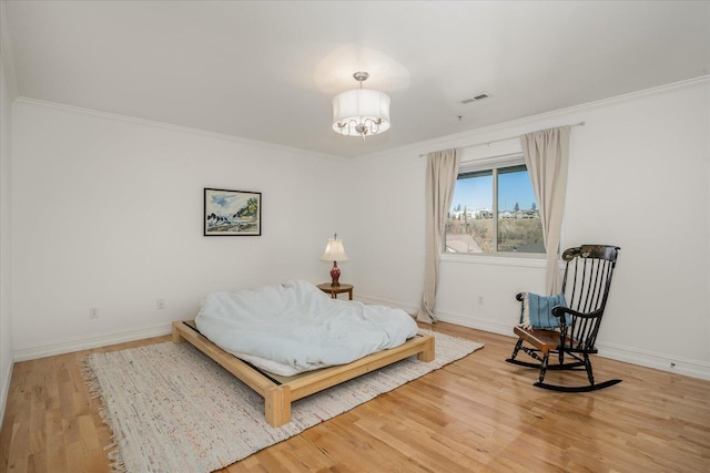 bedroom with visible vents, baseboards, wood finished floors, an inviting chandelier, and crown molding