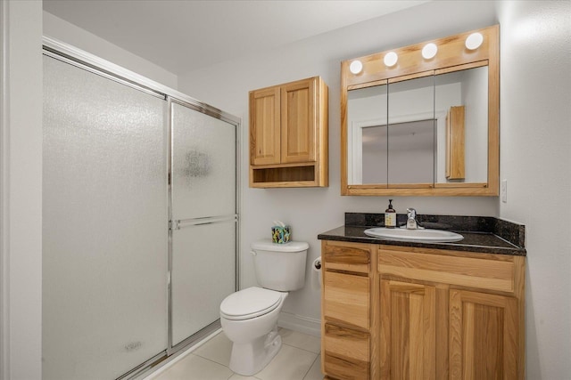 bathroom with toilet, vanity, baseboards, tile patterned floors, and a stall shower