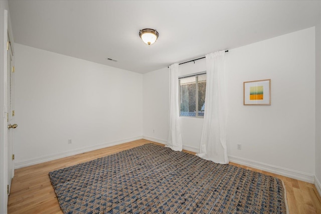 unfurnished room with visible vents, light wood-style flooring, and baseboards