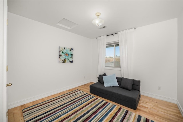 sitting room featuring light wood finished floors, attic access, visible vents, and baseboards