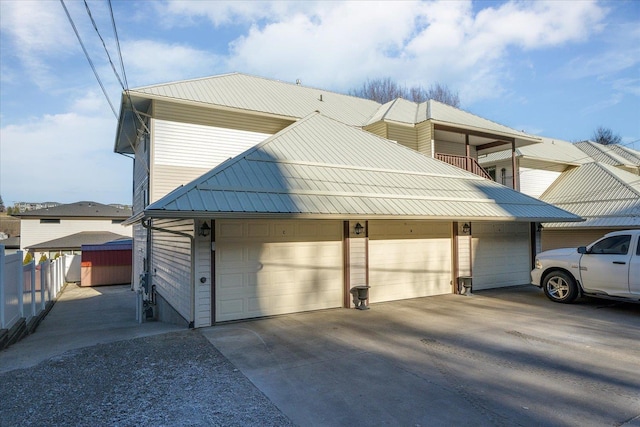 view of property exterior with a garage, fence, metal roof, and concrete driveway