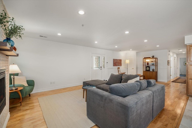 living room with recessed lighting, a large fireplace, visible vents, baseboards, and light wood finished floors