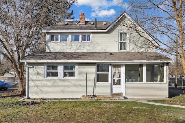 back of property with a lawn, a chimney, and a sunroom