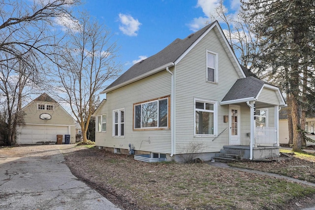 view of front of house featuring roof with shingles, a detached garage, and an outbuilding