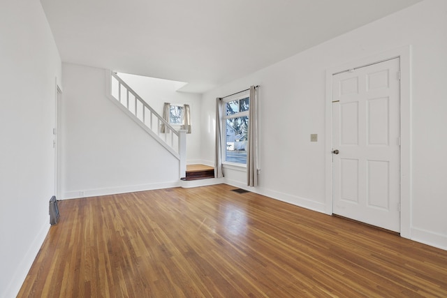 entrance foyer featuring baseboards, visible vents, stairway, and wood finished floors