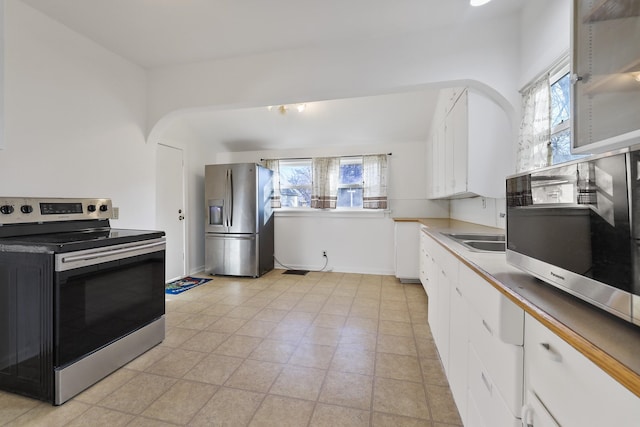 kitchen with appliances with stainless steel finishes, light countertops, a healthy amount of sunlight, and white cabinetry