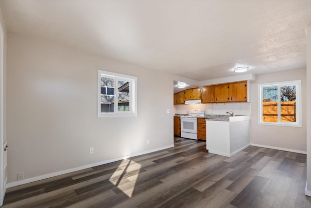 kitchen featuring dark wood-style floors, white stove, brown cabinets, and baseboards