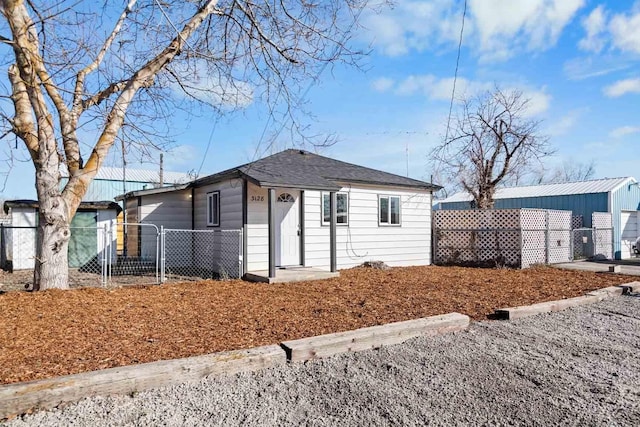 view of front of property with roof with shingles, fence, and a gate