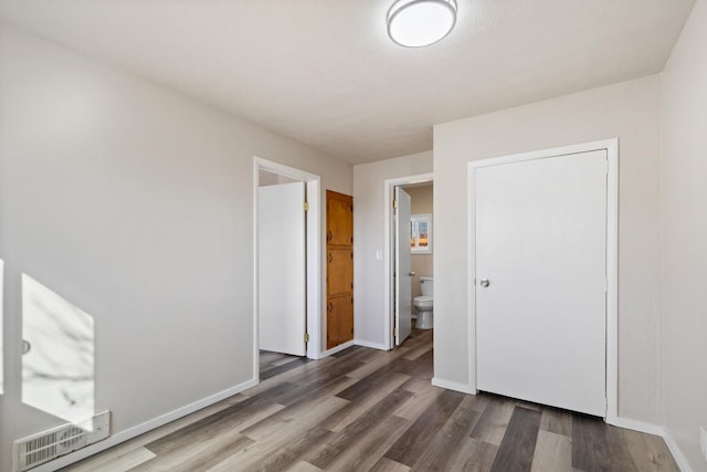 unfurnished bedroom featuring visible vents, baseboards, and wood finished floors