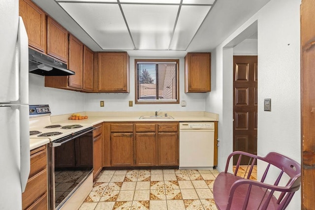 kitchen featuring white appliances, brown cabinetry, light countertops, under cabinet range hood, and a sink