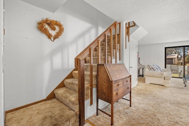 stairway with a textured ceiling, carpet, and baseboards