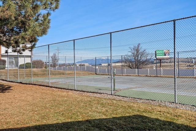 view of tennis court with community basketball court and fence