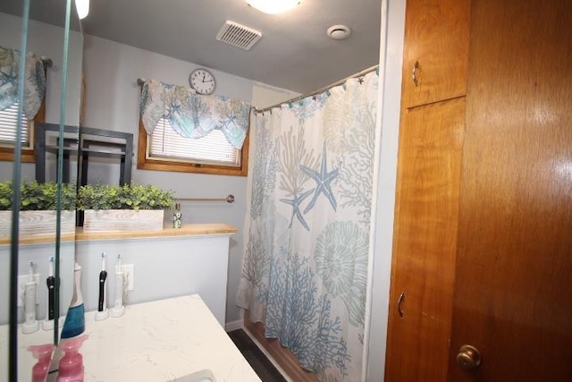 bathroom featuring curtained shower, plenty of natural light, and visible vents