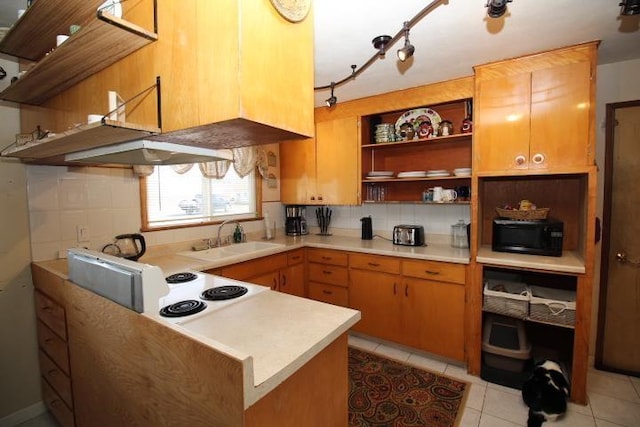 kitchen with black microwave, light countertops, a sink, and open shelves