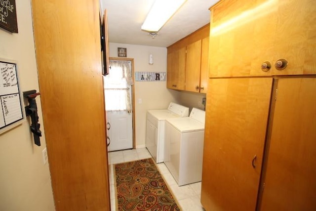 washroom with cabinet space, washing machine and dryer, and light tile patterned floors