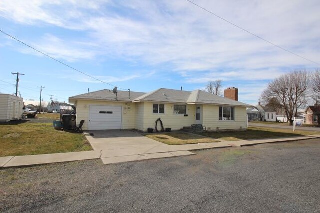 ranch-style house with a garage, driveway, a chimney, and a front yard