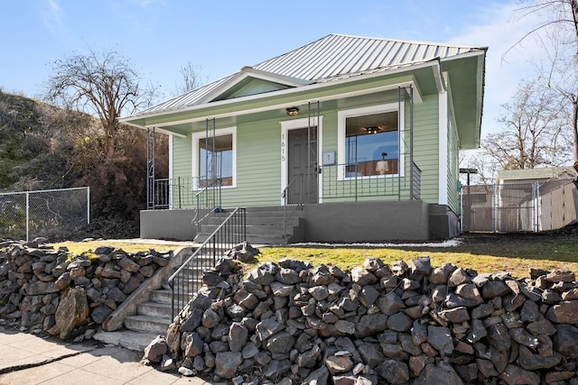 view of front of home featuring covered porch, metal roof, and fence