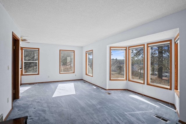 carpeted spare room with visible vents, a textured ceiling, and baseboards