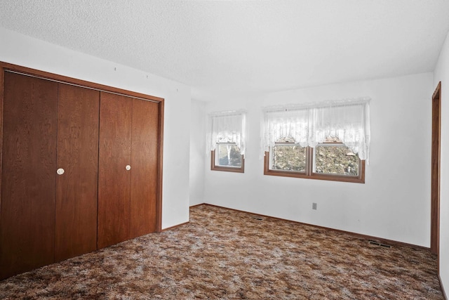 unfurnished bedroom with carpet floors, a textured ceiling, and a closet