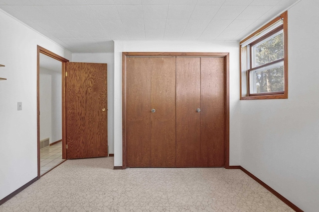 unfurnished bedroom with baseboards, visible vents, and a closet