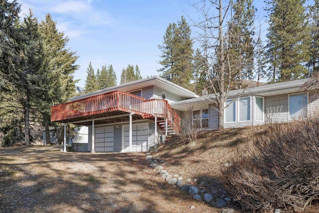 view of front of home featuring dirt driveway, stairway, and a deck