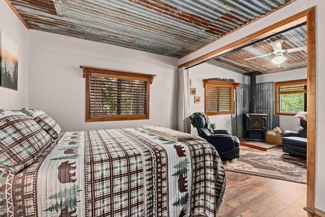 bedroom featuring wood ceiling, a wood stove, beam ceiling, and hardwood / wood-style flooring